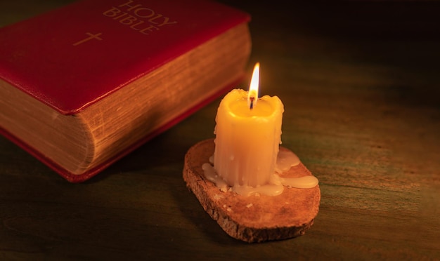 Cerca de una biblia cerrada y una vela encendida sobre un fondo de madera