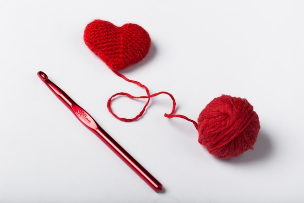 Cerca de una bola de lana y forma de corazón sobre fondo blanco. Hilo de lana en forma de corazón. Me encanta el crochet.