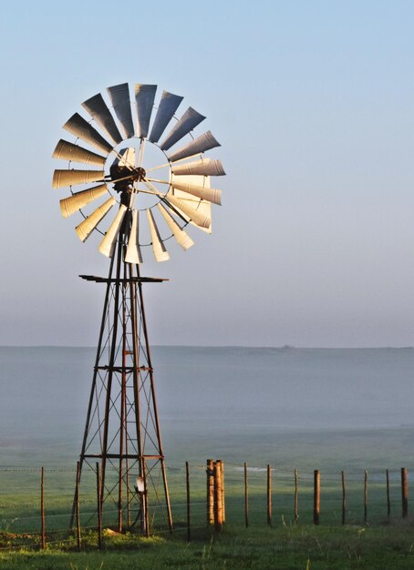 Cerca de una bomba de agua de molino de viento con niebla matutina