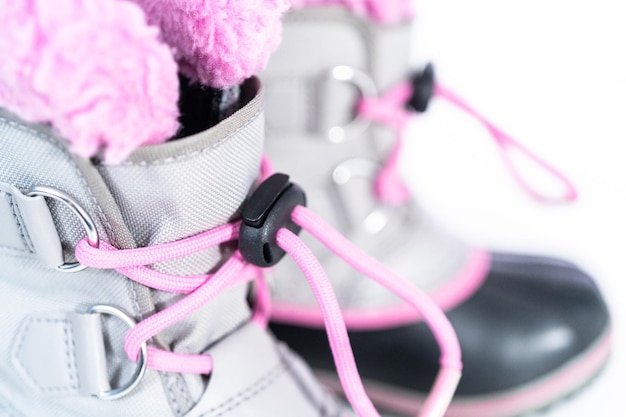 De cerca. Botas de invierno cálidas e impermeables de color rosa y gris para niña sobre un fondo blanco.