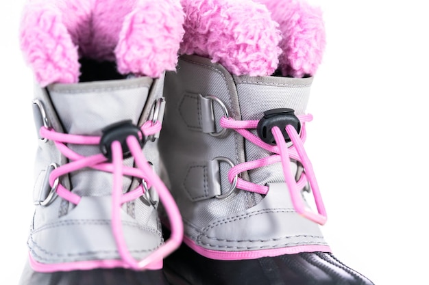 De cerca. Botas de invierno cálidas e impermeables de color rosa y gris para niña sobre un fondo blanco.
