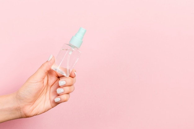 Cerca de la botella de cosméticos en mano femenina