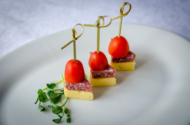 Cerca de brochetas con tomate cherry, queso y salami