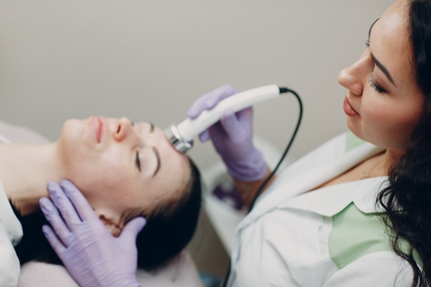 Cerca de la cabeza de la mujer que recibe terapia facial de fonoforesis de electroporación en el salón de belleza spa.