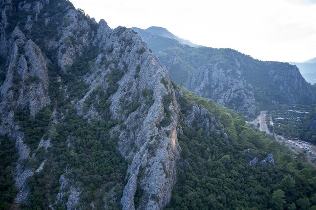 Cerca de una cadena montañosa con árboles verdes sobre la carretera. Vista del acantilado rocoso escénico el día de verano. Fondo de naturaleza.