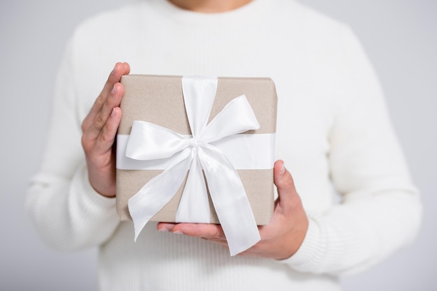 Cerca de caja de regalo de navidad envuelto en manos masculinas sobre fondo gris