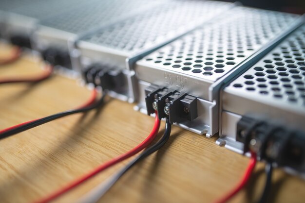 Foto cerca de las cajas de malla metálica de la fuente de alimentación y cables sobre una mesa de madera