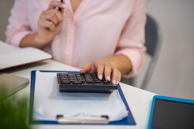 Cerca de una calculadora en uso por una agradable joven mientras cuenta