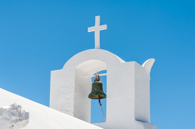 Cerca de un campanario blanco con cruz en Santorini