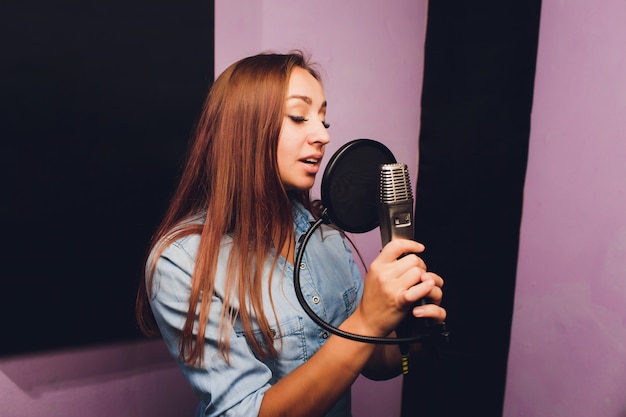 Foto cerca de un cantante grabando una pista en un estudio.