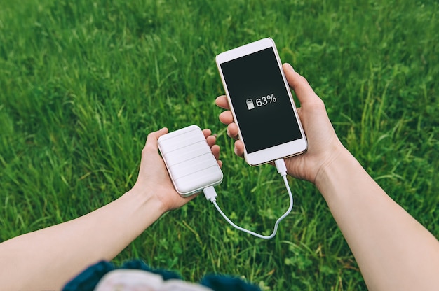 Cerca de cargar el teléfono desde el banco de energía en las manos