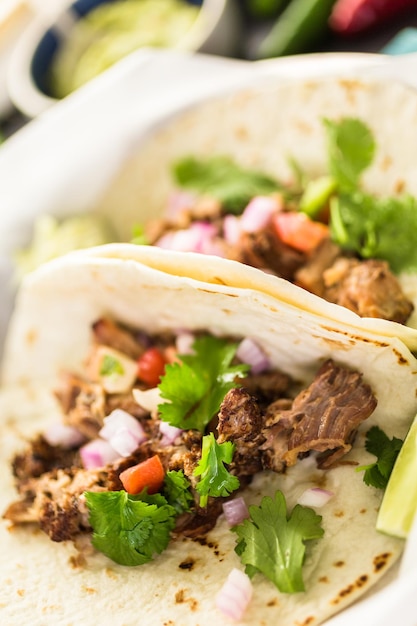 Cerca de carnitas de cerdo desmenuzado con pico de gallo sobre una tortilla de harina.