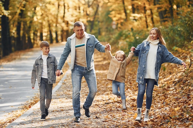 Cerca de la carretera La familia feliz está en el parque en otoño juntos