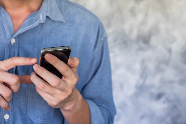 Cerca de Casual hombre usando teléfono inteligente sobre fondo grunge