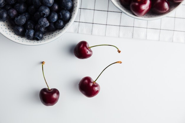 Cerca de cerezas y arándanos en tazones