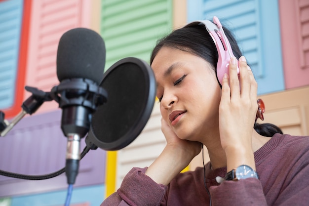 Cerca de una chica asiática fresca escuchando con auriculares durante el podcast