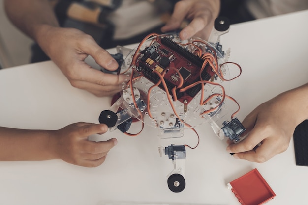 De cerca. El chico recoge un robot araña con dos niños pequeños.