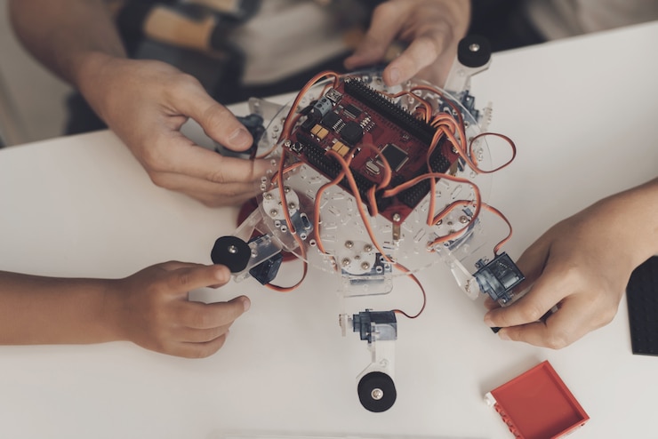 Foto de cerca. el chico recoge un robot araña con dos niños pequeños.
