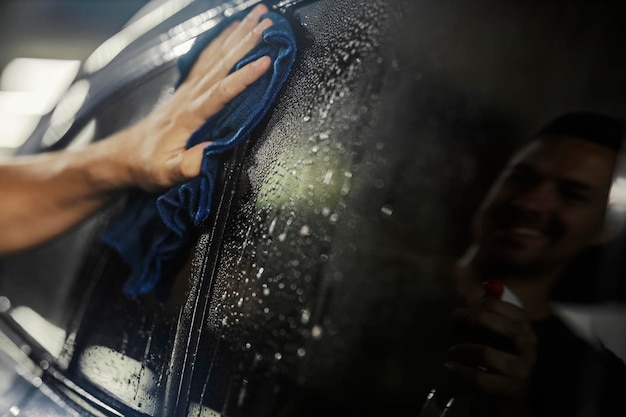 Foto cerca de un coche de limpieza de mano con alfombra con reflejo en una ventana