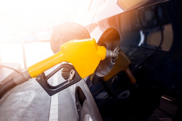 Foto cerca del coche está rellenando combustible combustible en la estación de servicio