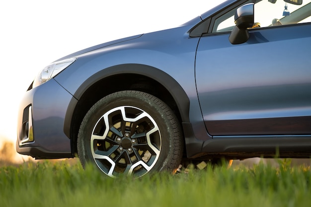 Cerca del coche todoterreno azul sobre la hierba verde. Viajar en automóvil, aventurarse en la vida silvestre, expedición o viajes extremos en un automóvil SUV. Vehículo todoterreno 4x4 en campo al amanecer.