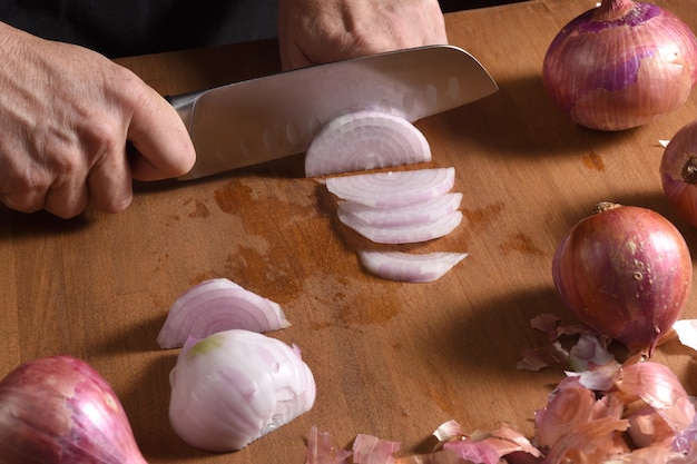 Foto cerca de un cocinero pelando una cebolla en una madera