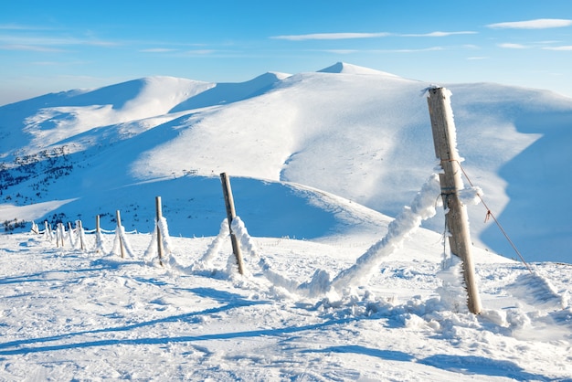 Cerca com gelo e neve na aldeia alpina de inverno. Paisagem montanhosa