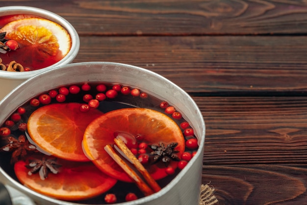 Cerca de copa de vino caliente con especias y bayas en mesa gris