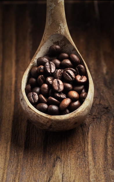 Cerca de una cuchara de madera con granos de café