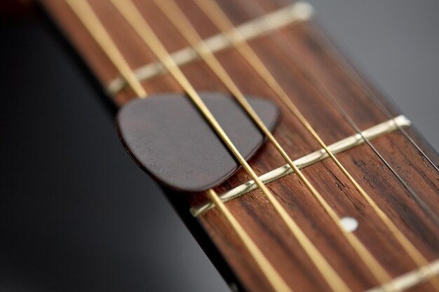 cerca del cuello de la guitarra con la pica entre las cuerdas