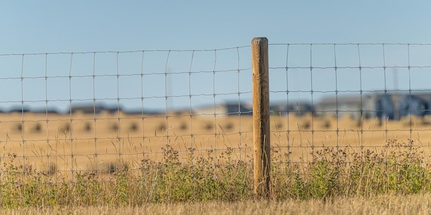 Cerca de arame com campos agrícolas atrás dela