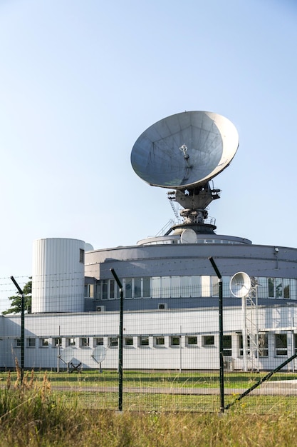 Cerca de arame farpado em torno do centro de links de satélite com torre de telecomunicações equipada com antenas de radar cibercrime e conceito de cibersegurança