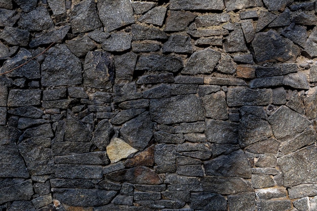 Cerca de pedra. cerca de pedras pretas de forma irregular. uma cerca de pedras lascadas. textura de pedra.