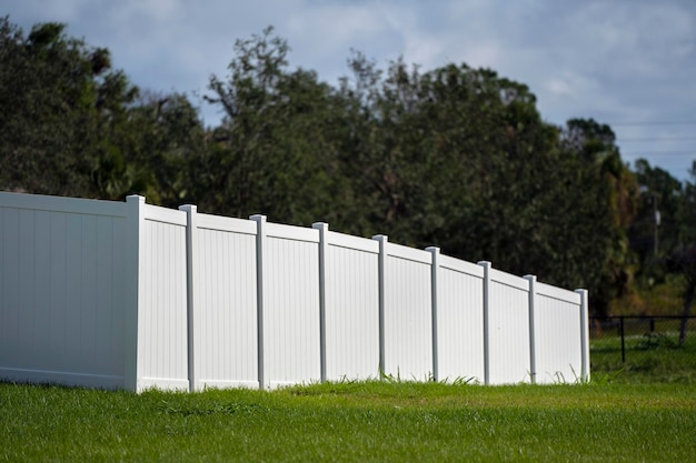 Foto cerca de piquete de vinil branco no gramado verde ao redor da propriedade para proteção e privacidade do quintal