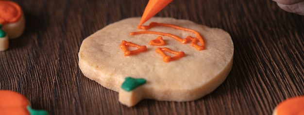 Cerca de decorar lindas galletas de jengibre de calabaza de Halloween con glaseado