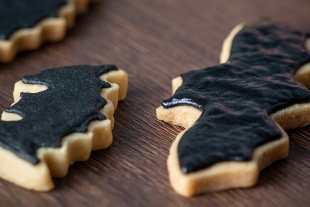 Cerca de decorar lindas galletas de jengibre de murciélago de Halloween con una bolsa de cobertura de crema glaseada.