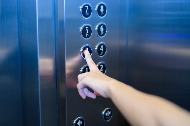 Foto cerca del dedo humano está presionando el botón del elevador
