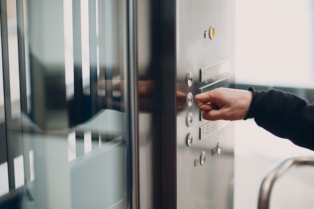 Cerca del dedo índice presionando el botón del elevador durante el concepto de cuarentena covid-19 de la pandemia de coronavirus