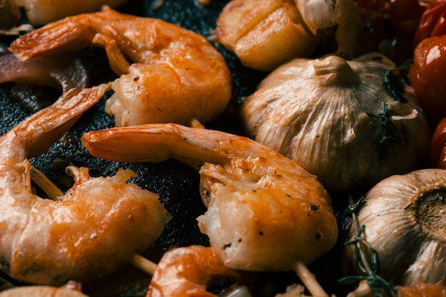 Cerca de deliciosas gambas fritas con corteza crujiente en palos de madera y ajo guisado cerca