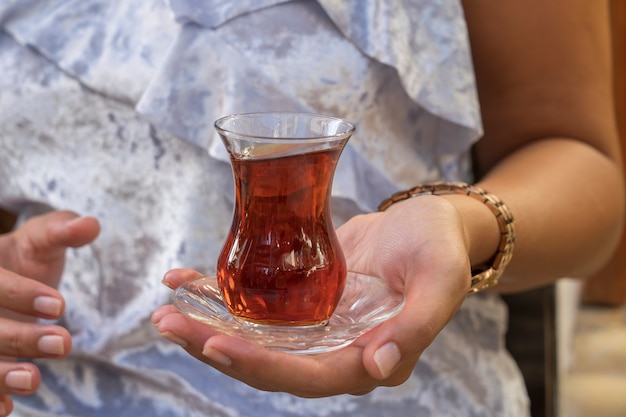 Cerca de delicioso té rojo turco con cristal en forma de pera tradicional en la mano de la mujer, Turquía