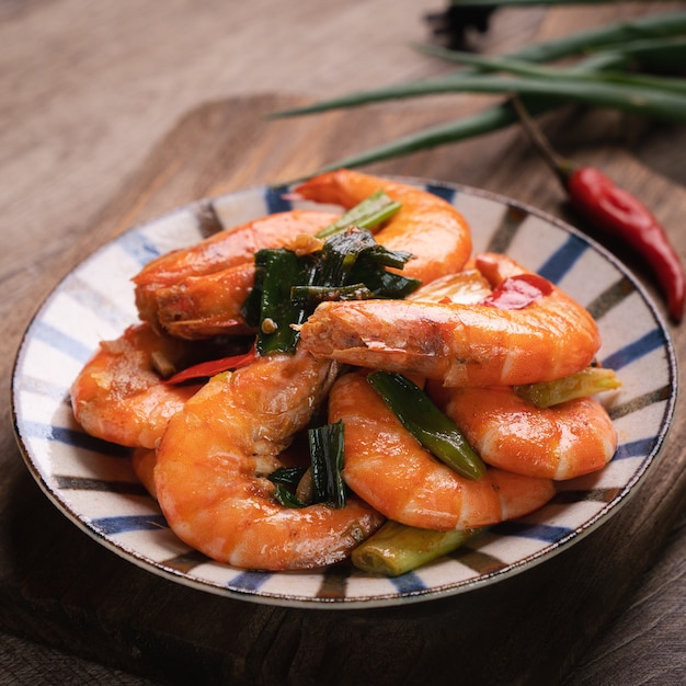 Cerca de deliciosos camarones fritos caseros en un plato sobre la mesa de madera oscura.