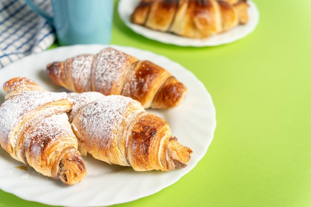 Cerca de deliciosos croissants de chocolate espolvoreados con azúcar fina con una taza de café