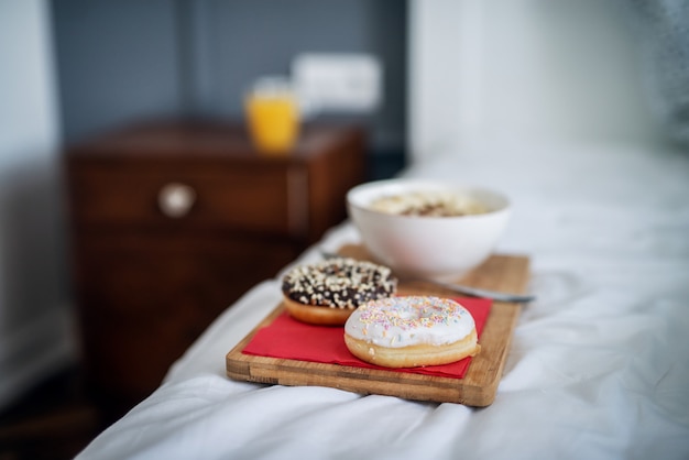 Foto cerca del desayuno o la cena en un platillo de madera dejado en la cama en casa o en el hotel.