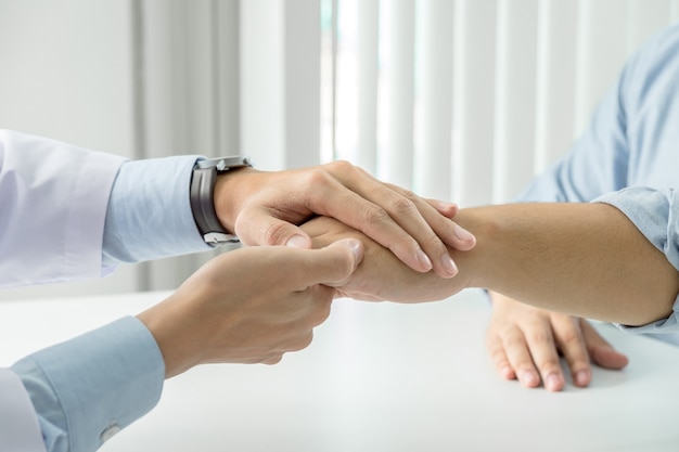 Cerca del doctor tocando la mano del paciente