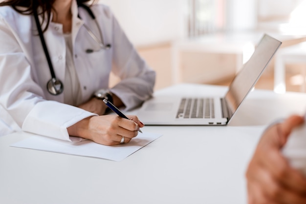 Foto cerca de la doctora escribiendo papel de prescripción