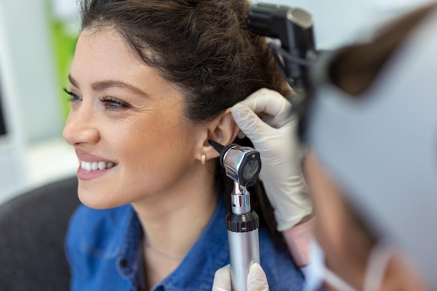 Foto cerca de una doctora sosteniendo cuidadosamente la oreja de su paciente para establecer una visión más clara del interior de su oído para ver si necesita audífonos en una clínica moderna