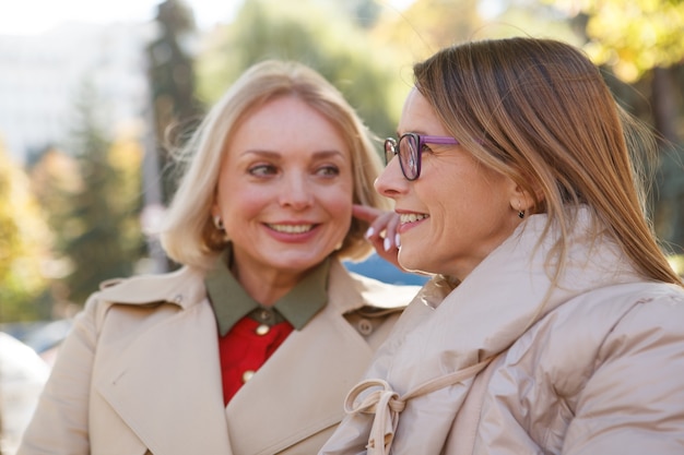 Cerca de dos amigas maduras felices hablando y riendo al aire libre