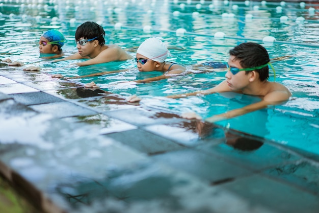 Foto cerca de dos chicas adolescentes y un niño con gafas de natación haciendo un flotador