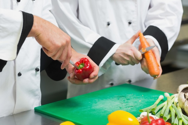 Foto cerca de dos cocineros cortar verduras