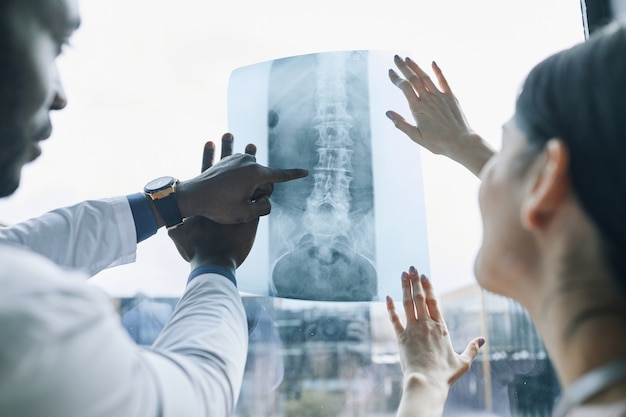 Cerca de dos médicos mirando imágenes de rayos x contra la ventana, espacio de copia